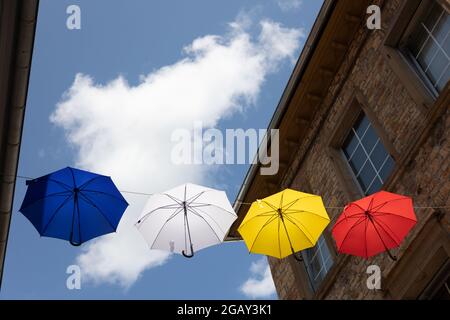 Colourful umbrellas hang on a rope between houses above the pedestrian zone of Bad Kreuznach, Rhineland-Palatinate, Germany. Stock Photo