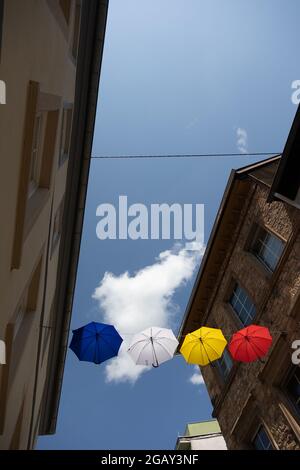 Colourful umbrellas hang on a rope between houses above the pedestrian zone of Bad Kreuznach, Rhineland-Palatinate, Germany. Stock Photo