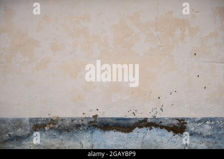 Old plastered with wall with blue skirting board and peeling paint, traditional mediterranean architecture background Stock Photo
