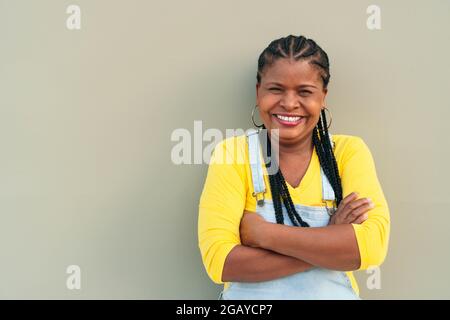 African American woman with long hair and braids standing on a gray wall - happiness Stock Photo
