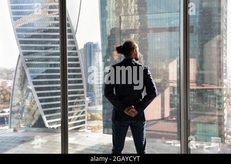 Confident young african american businessman in suit standing near window. Stock Photo