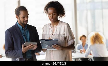 Concentrated two african colleagues discussing working issues. Stock Photo