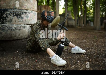 Female paintball player sitting on the ground Stock Photo