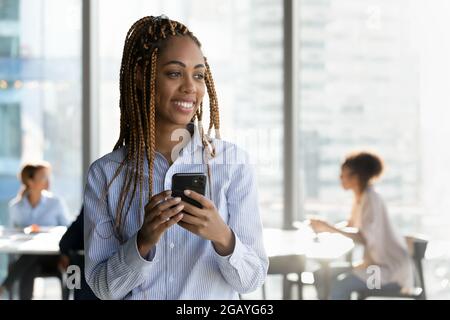 Dreamy happy young african businesswoman looking in distance. Stock Photo