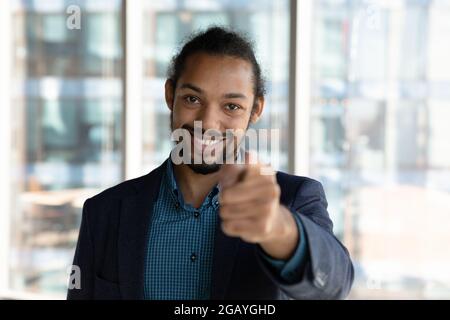 Smiling friendly young african businessman pointing finger at camera. Stock Photo