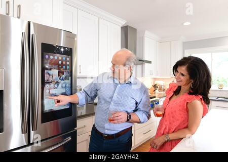 A couple uses a Samsung Smart refrigerator in their home kitchen with a touch screen and WIFI Stock Photo