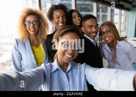 Smiling african woman making selfie with motivated colleagues. Stock Photo
