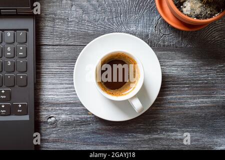Cup of coffee, laptop, cactus on a wooden table, top view, flat lay. Workplace at home. Online Education. Stock Photo