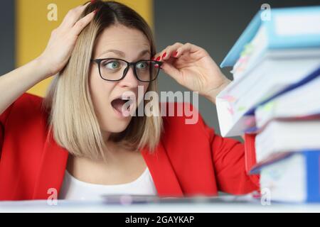 Scared young businesswoman secretary with huge stack of folders Stock Photo