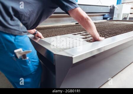 Worker placing work piece on table of jet cutting machine Stock Photo