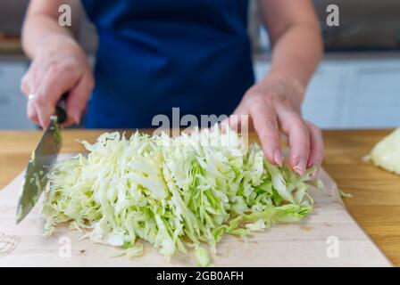 Chef slices cabbage to make healthy vegetable salad. Stock Photo