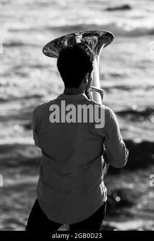 A musician play a tuba on the seashore. Black and white photo. Stock Photo