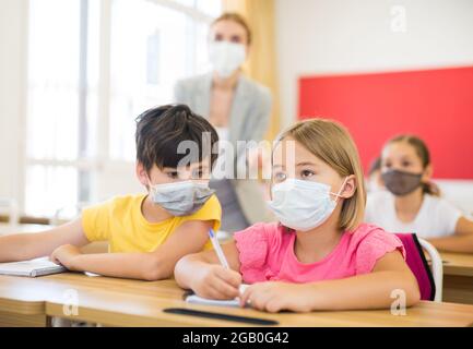 Kid in mask cheating during test Stock Photo