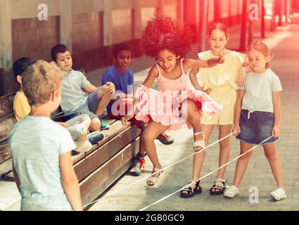 Mexican girl playing rubber band jumping game with european friends Stock Photo