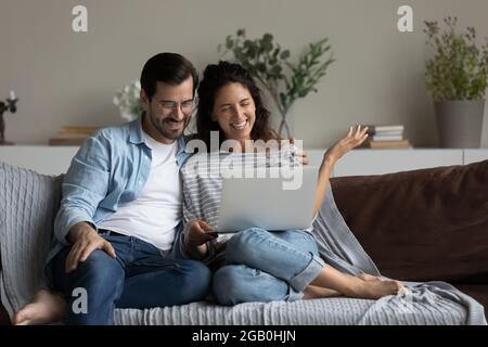 Happy millennial couple using laptop for video call from home Stock Photo