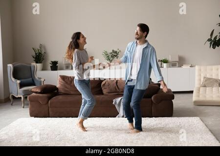 Happy excited millennial couple dancing together in living room Stock Photo