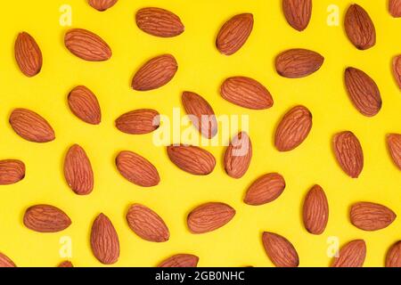Top view of unshelled almond nuts kernels. Flat lay with food composition on yellow background. Stock Photo