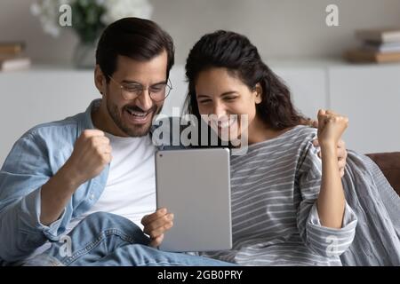 Happy excited 30s couple using tablet at home Stock Photo