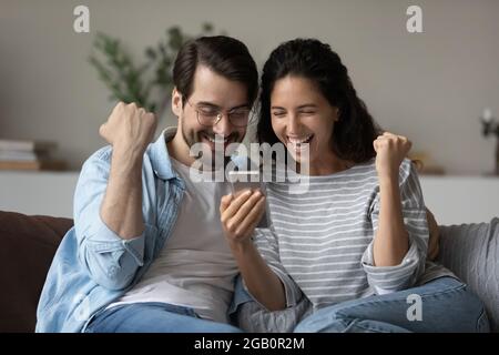 Excited joyful family couple using smartphone, looking at screen Stock Photo