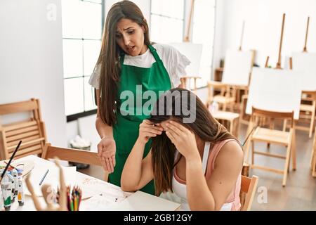 Two latin paint students arguing sitting on the table at art school. Stock Photo