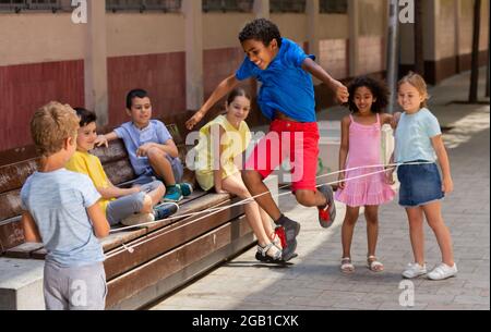 Mexican boy playing rubber band jumping game with friends Stock Photo