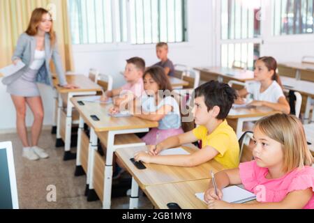 Focused preteen pupils studying in classroom with female teacher Stock Photo