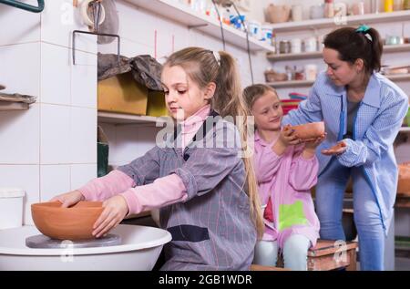 teacher helping teenagers at making pottery during arts and crafts class Stock Photo