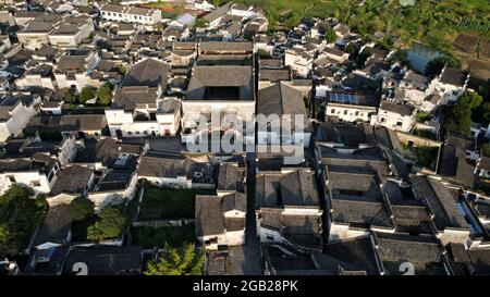 (210802) -- HEFEI, Aug. 2, 2021 (Xinhua) -- Ancient streets and houses are seen from above in Xidi Village, Yixian County of Huangshan City, east China's Anhui Province, July 29, 2021. It is a serene night as the luminous moon gleams in the sky. With a gong and mallet in hand, Lu Lei sets out to perform 'dageng'. Lu, a post-80s man, has been a night watchman as a substitute for his father, a member of Xidi's 'dageng' team, in the ancient village loved by many for its picturesque scenery. Lu works at a tourism company in the county seat of Yixian during the day and returns home in Xidi afte Stock Photo