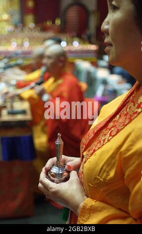 During prayers at Buddha Tooth Relic Temple and Museum in Chinatown, Singapore, a woman is holding a Buddhist ritual object