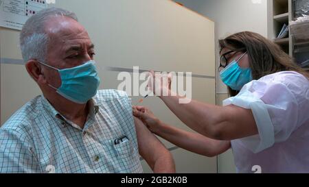 An Israeli health worker administers a third dose of the Pfizer-BioNtech COVID-19 vaccine to an elderly man at Maccabi Health Services on August 01, 2021 in Jerusalem, Israel. Israel started administering a third dose of the Pfizer Covid-19 vaccine to people over 60 due to concern about the more virulent Delta variant, making Israel the first country in the world to do so. Stock Photo