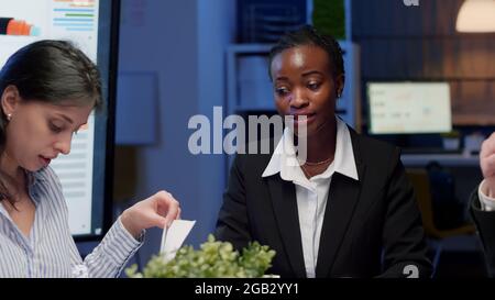 African american businesswoman brainstorming business strategy working in meeting room late at night. Diverse multi ethnic teamwork planning company management presentation working at ideas Stock Photo