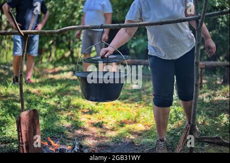 Midsection of woman preparing food on campfire in nature Stock Photo