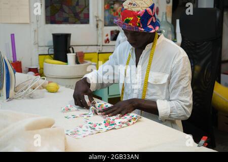 An african tailor cutting fabric in his sewing shop. Stock Photo