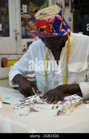 An african tailor cutting fabric in his sewing shop. Stock Photo