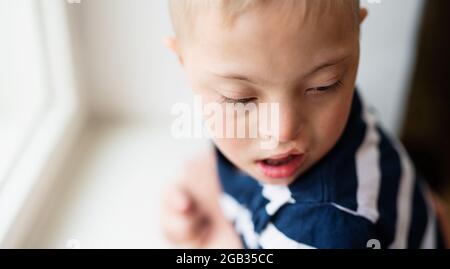 Close-up portrait of down syndrome boy indoors at home. Copy space. Stock Photo