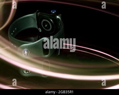 Single smart watch displayed with rays light effect background on dark backdrop. Stock Photo