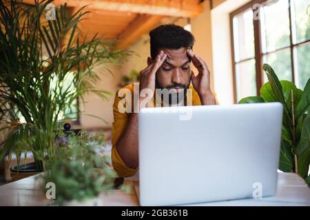Frustrated young man with laptop working indoors, home office concept. Stock Photo