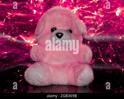 Soft toy teddy bear isolated on pink light sparkles background. Stock Photo