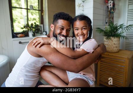 Happy young man with small sister indoors at home, hugging. Stock Photo