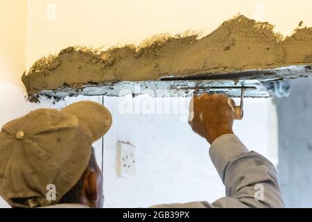 Worker plastering cement mortar on concrete ceiling beam with trowel Stock Photo