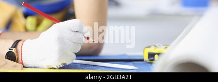 Woman architect in gloves drawing with pencil on blueprint closeup Stock Photo