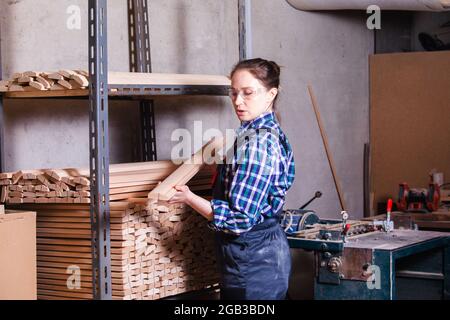 Female apprentice checking wooden plank at carpentry workshop Stock Photo