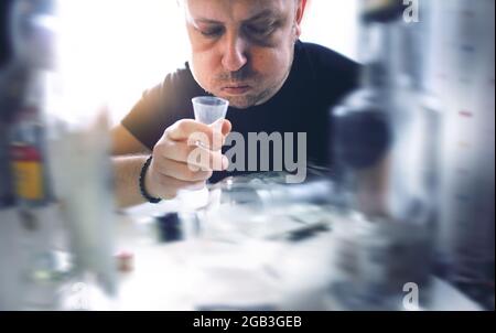 Destroyed by alcohol and addicted, the man drinks alcohol alone Stock Photo