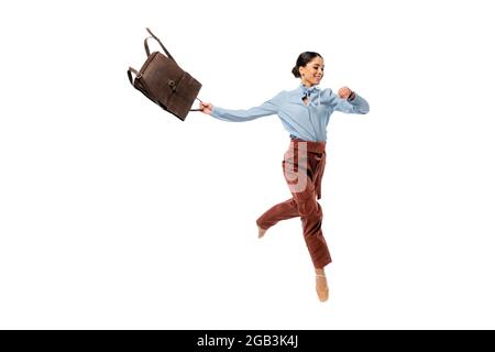 Cheerful ballerina looking at wristwatch while holding backpack isolated on white Stock Photo