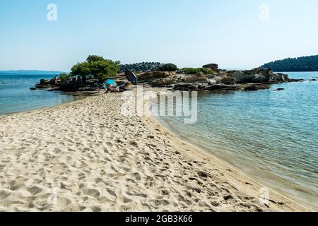 Lagonisi Beach - Sithonia, Chalkidiki, Greece - JULY 8, 2021: Aegean sea coast landscape and beautiful samll beach in the cove Stock Photo