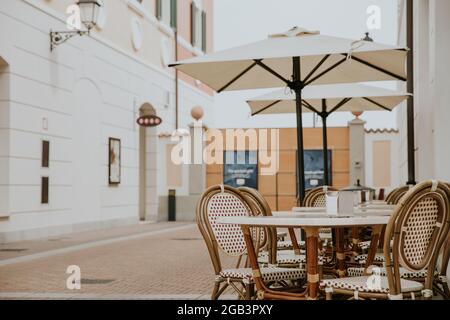An empty table in the outdoor restaurant or cafe in Venice outlet. Decorated with glass bottle of beer and beautiful white flower on the table. Stock Photo
