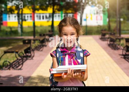 Girl schoolgirl with a heavy stack of books isolated Stock Photo - Alamy