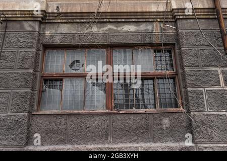 big dirty broken window. dark wall of a large house. Vintage architecture classical facade old gray building front view Stock Photo