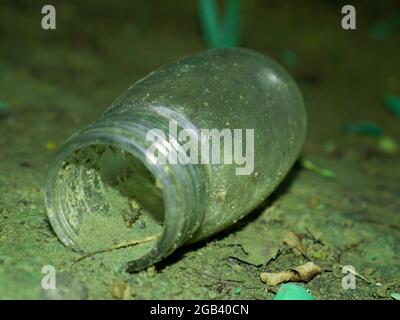 Medicated glass bottle lying on soil field, Nature pollution concept presenting through glass object. Stock Photo