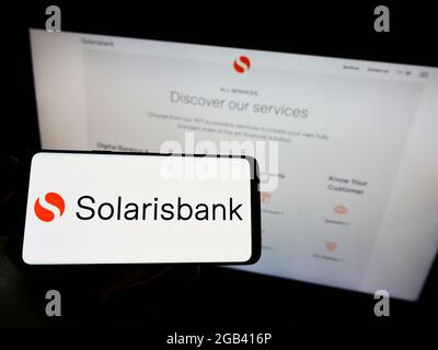 Person holding cellphone with logo of German financial services company Solarisbank AG on screen in front of webpage. Focus on phone display. Stock Photo